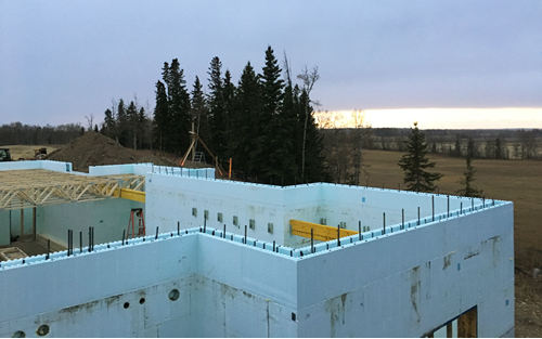 Photograph of ICF-built structure. The building is not completed. The walls are made of Nudura ICF and there is rebar sticking out of the top of the ICF blocks.