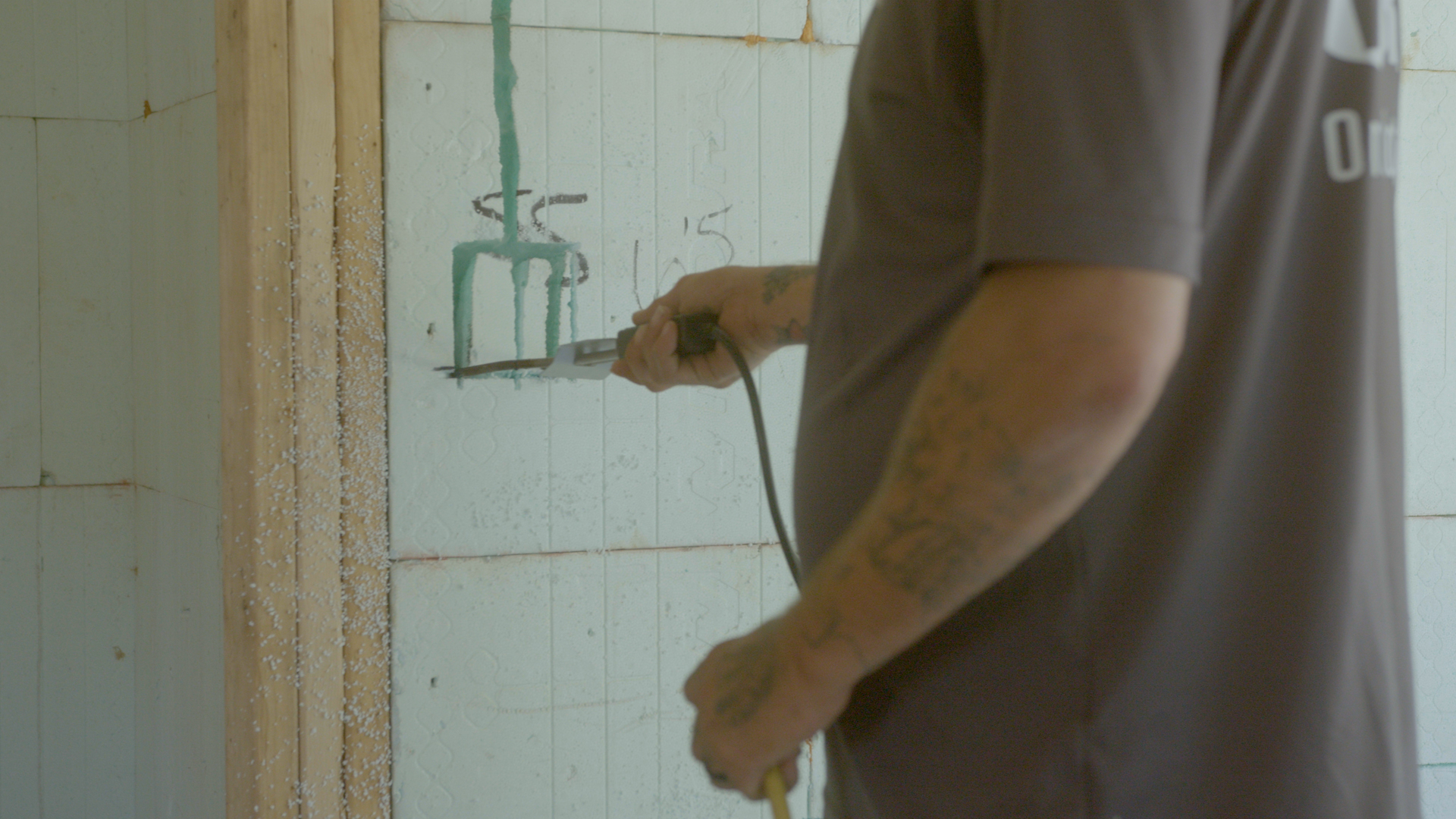 a man uses a hot knife to cut into a nudura ICF block