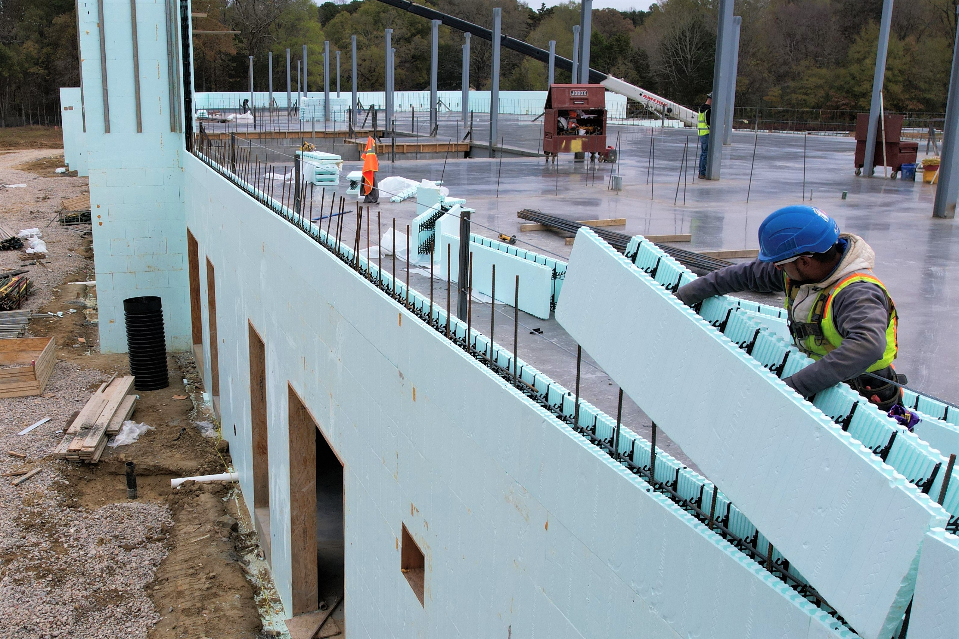 a man wearing a hard hat stacks an ICF block on top of another